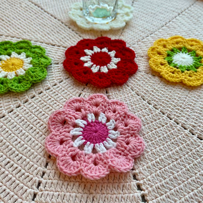Terracotta and rust crochet flower coaster with green leaf details on a warm beige background